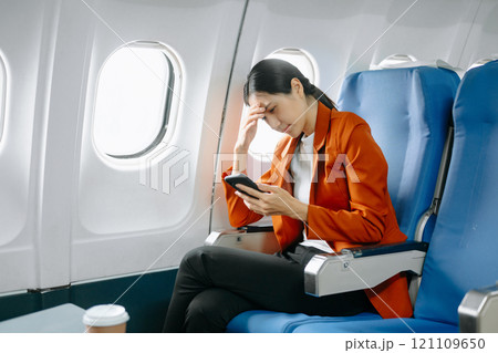 Photo of a frustrated woman sitting on an airplane with her head in her hands. Asian woman sitting 121109650