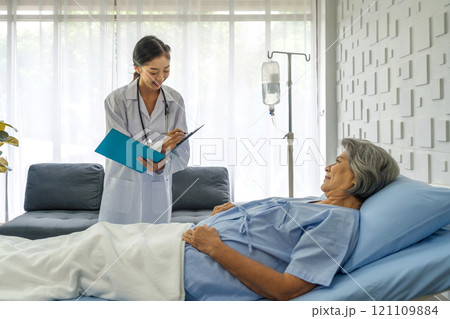 Young asian doctor in white gown with stethoscope and document folder, examine the symptom of the elderly patient in the recovery room. Healthcare and medicine concept Young asian doctor in white gown with stethoscope and document folder, examine the symptom of the elderly patient in the recovery room. Healthcare and medicine concept 121109884