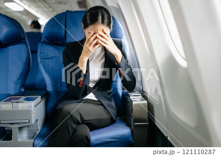 Photo of a frustrated woman sitting on an airplane with her head in her hands. Asian woman sitting 121110287