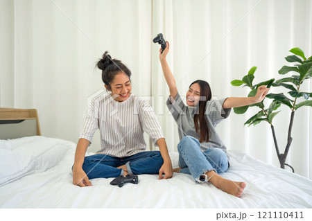 Two asian teenage girls playing  console games in bed. 121110411