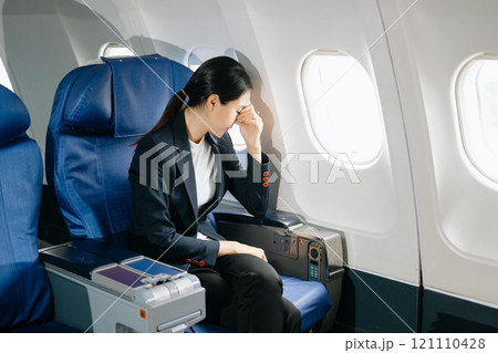 Photo of a frustrated woman sitting on an airplane with her head in her hands. Asian woman sitting 121110428