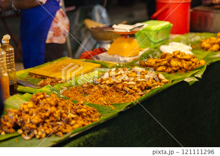 Authentic Thai street food displayed on banana leaves at a bustling market 121111296