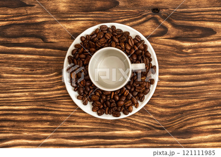 On the saucer is a cup of an empty cup for coffee and lie coffee beans 121111985