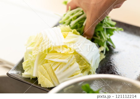 白菜と水菜を皿に盛り付ける男性の手 白菜と水菜を皿に盛り付ける男性の手 121112214