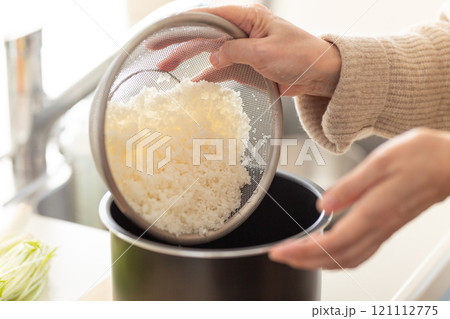 研いだ米を炊飯ジャーの内釜に入れる女性の手元 研いだ米を炊飯ジャーの内釜に入れる女性の手元 121112775