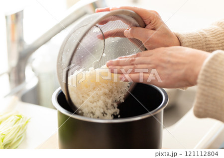 研いだ米を炊飯ジャーの内釜に入れる女性の手元 121112804