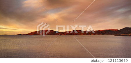 Landscape of lagoon mountains and sunset clouds over calm and serene polar arctic lake in Norway. Scenic view of barren hills in remote area. Traveling abroad and overseas for holiday and vacation 121113659