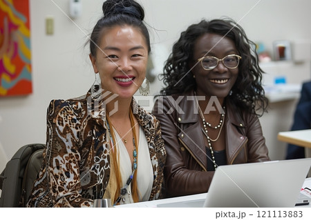 Two smiling women enjoying a collaborative environment, showcasing friendship and teamwork. 121113883