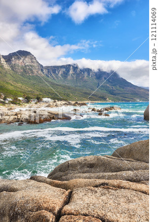 Landscape view of ocean beach, sea, clouds, blue sky with copy space on Camps Bay, Cape Town, South Africa. Tidal waves washing on shoreline rocks or boulders. Background of Twelve Apostles mountains Landscape view of ocean beach, sea, clouds, blue sky with copy space on Camps Bay, Cape Town, South Africa. Tidal waves washing on shoreline rocks or boulders. Background of Twelve Apostles mountains 121114069