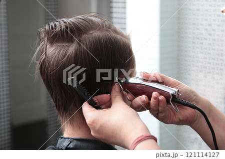 Barbershop. Haircuts for men. Men's hair. Barber shop master gives haircut perfect shape with an electric razor. Back view. 121114127