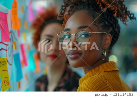Two women engaged in a creative brainstorming session with colorful sticky notes. Two women engaged in a creative brainstorming session with colorful sticky notes. 121114182