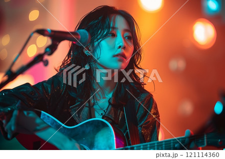 A musician performs passionately on stage under vibrant lights. A musician performs passionately on stage under vibrant lights. 121114360