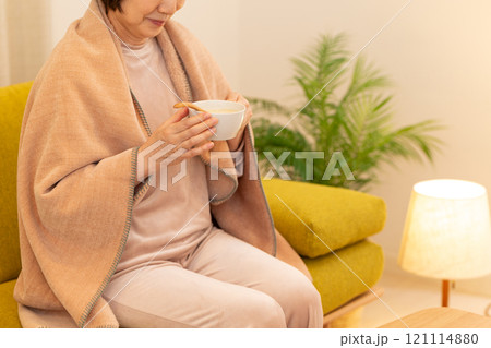 冬の夜のリビングでポタージュスープを食べるミドル女性 121114880
