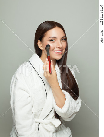 Perfect young woman applying make with a blush brush Perfect young woman applying make with a blush brush 121115114