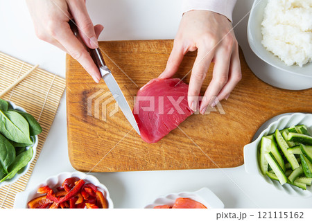 In the process of making sushi, preparing all the ingredients for sushi, the girl cuts the tuna. View from above. 121115162