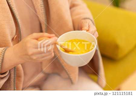 冬の夜のリビングでコーンポタージュスープを食べるミドル女性 121115181