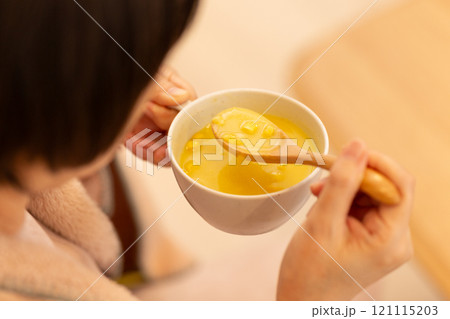 冬の夜のリビングでコーンポタージュスープを食べるミドル女性 121115203