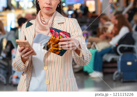 Caucasian woman in a jacket checks her passport data with her ticket on her smartphone. The concept of an online travel app Caucasian woman in a jacket checks her passport data with her ticket on her smartphone. The concept of an online travel app 121115226