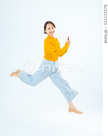 スマホを持ってジャンプする女性の全身写真 121115578