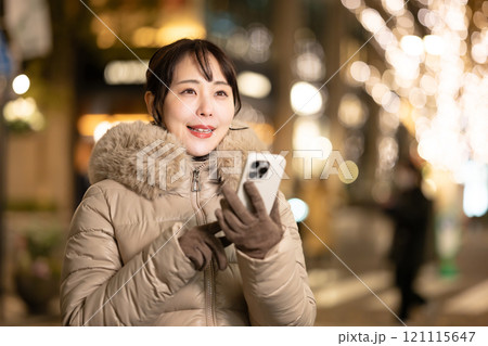 スマホを持ってイルミネーションを見る女性 121115647