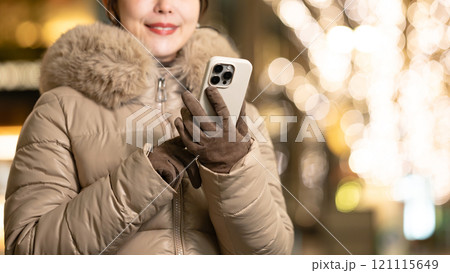 スマホを持ってイルミネーションを見る女性 121115649