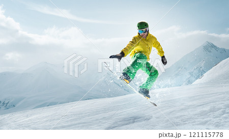 athlete man performing tricks on snowboard, exuding confidence and control in vibrant winter gear against clear skies and alpine scenery. 121115778