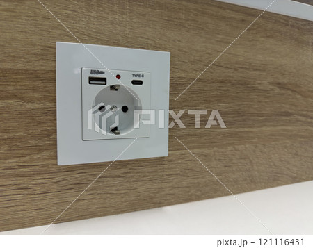 Modern socket on wooden wall with USB and type c connectors 121116431