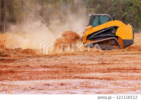 On construction site, bulldozer is leveling ground graded soil for preparing construction. 121116512