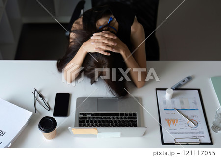 Stressed Office Worker Overwhelmed with Workload at Desk in Modern Corporate Environment Stressed Office Worker Overwhelmed with Workload at Desk in Modern Corporate Environment 121117055