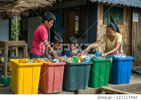 A family is sorting through trash and putting bottles in the appropriate bins. Scene is one of responsibility and environmental awareness 121117442