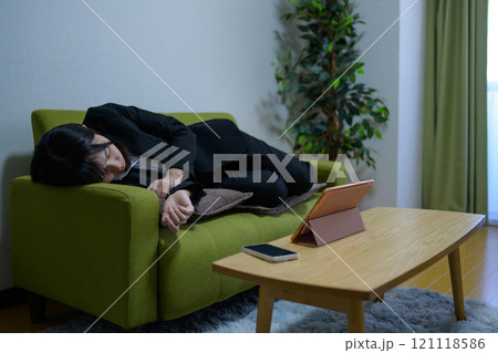 タブレットを見ながらソファで寝落ちして眠る一人暮らしの女性 ビジネスウーマン 残業 長時間労働 タブレットを見ながらソファで寝落ちして眠る一人暮らしの女性 ビジネスウーマン 残業 長時間労働 121118586