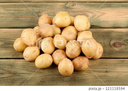A pile of washed unpeeled baby potatoes on a wooden surface. 121118594