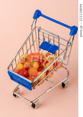 Mini tomatoes and peppers in a replica grocery cart with a blue handle. Mini tomatoes and peppers in a replica grocery cart with a blue handle. 121118644