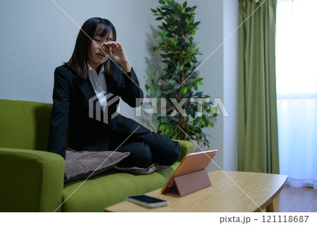 タブレットを見ながらソファで寝落ちして眠る一人暮らしの女性　寝起き　ビジネスウーマン　残業　 121118687