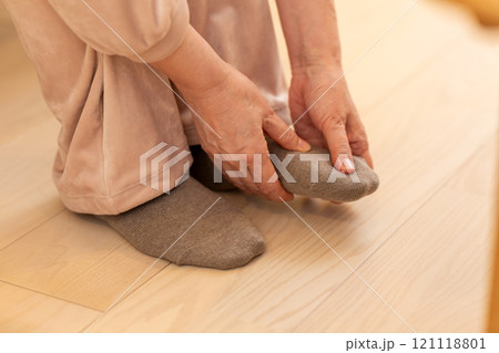 冬の夜のリビングで足先の冷えに苦しむミドル〜シニア女性 冬の夜のリビングで足先の冷えに苦しむミドル〜シニア女性 121118801