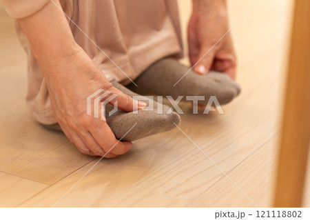 冬の夜のリビングで足先の冷えに苦しむミドル〜シニア女性 121118802
