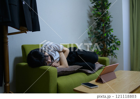 タブレットを見ながらソファで寝落ちして眠る一人暮らしの女性　ビジネスウーマン　仮眠　残業　疲労 121118803
