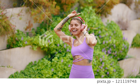A Joyful Woman Dancing Outdoors in a Stylish and Colorful Workout Outfit Full of Energy 121119748