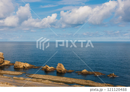 Calm ocean scene with unique coastal rock formations under a vibrant blue sky Calm ocean scene with unique coastal rock formations under a vibrant blue sky 121120488