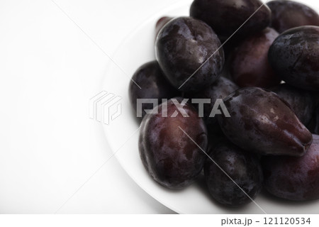 Fresh black plums on a white plate. Freshly washed plums. Juicy fruits. 121120534