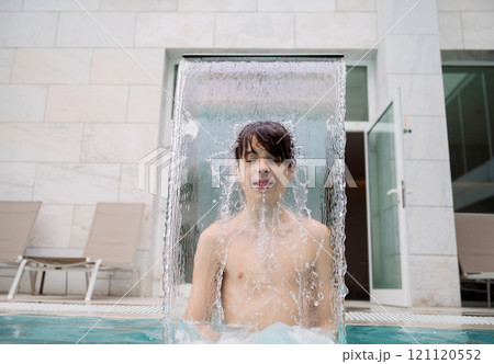 Boy under pool water stream Boy under pool water stream 121120552