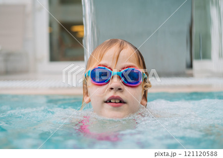 Girl in pool wearing goggles smiling 121120588