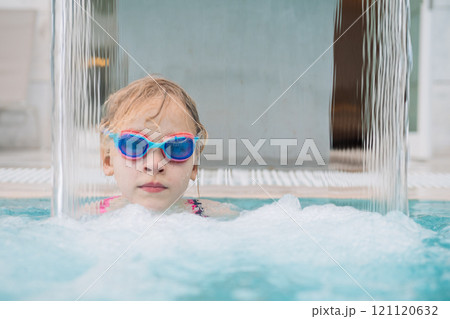 Girl wearing goggles under water stream Girl wearing goggles under water stream 121120632