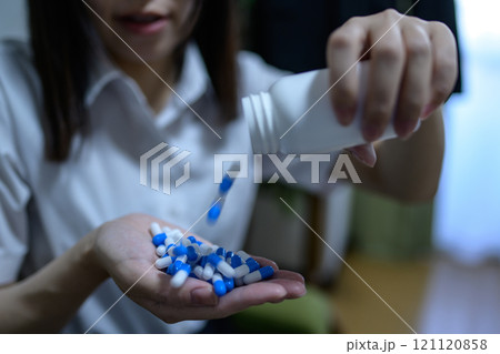 オーバードーズ　ODイメージ　大量の薬を接種する女性　薬物過剰摂取　ストレス　鬱病　残業　疲労　過労 121120858