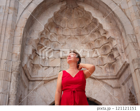 Woman in red dress walking narrow streets of old town Antalya during warm summer evening. Historic atmosphere and Mediterranean charm creates peaceful travel experience. near old mosque 121121151