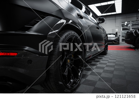 A close up view of a Lamborghini Urus Performante with a matte black finish in a showroom. The checkered floor and bright lighting highlight its design. 121121658