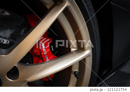 The image captures a detailed view of a McLaren 720S wheel, featuring a red brake caliper with the McLaren logo and a metallic gold rim. 121121754