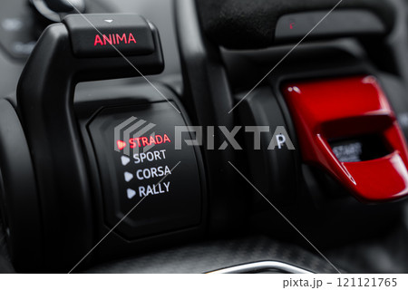 The image captures the driving mode selector in a Lamborghini Urus Performante, highlighting the 'Strada' mode in red. Black and red accents adorn the interior. The image captures the driving mode selector in a Lamborghini Urus Performante, highlighting the 'Strada' mode in red. Black and red accents adorn the interior. 121121765