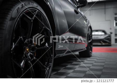 A close up view of a Lamborghini Urus Performante's sleek black exterior and Pirelli P Zero tires, with a McLaren 720S partially visible in an indoor showroom. A close up view of a Lamborghini Urus Performante's sleek black exterior and Pirelli P Zero tires, with a McLaren 720S partially visible in an indoor showroom. 121121777