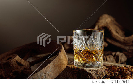 Whiskey in crystal glass on a old wooden board. 121122646